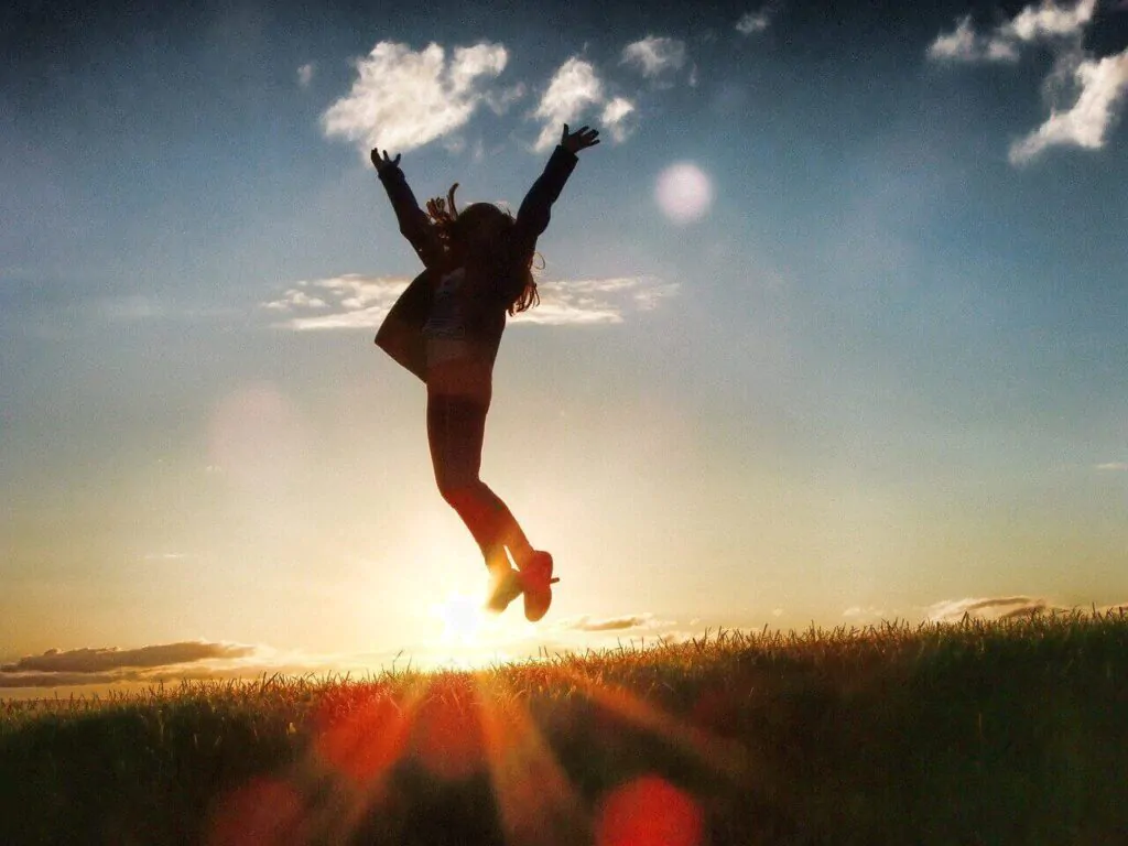 Mulher feliz e saltando para o alto com se estivesse comemorando uma vitória. 